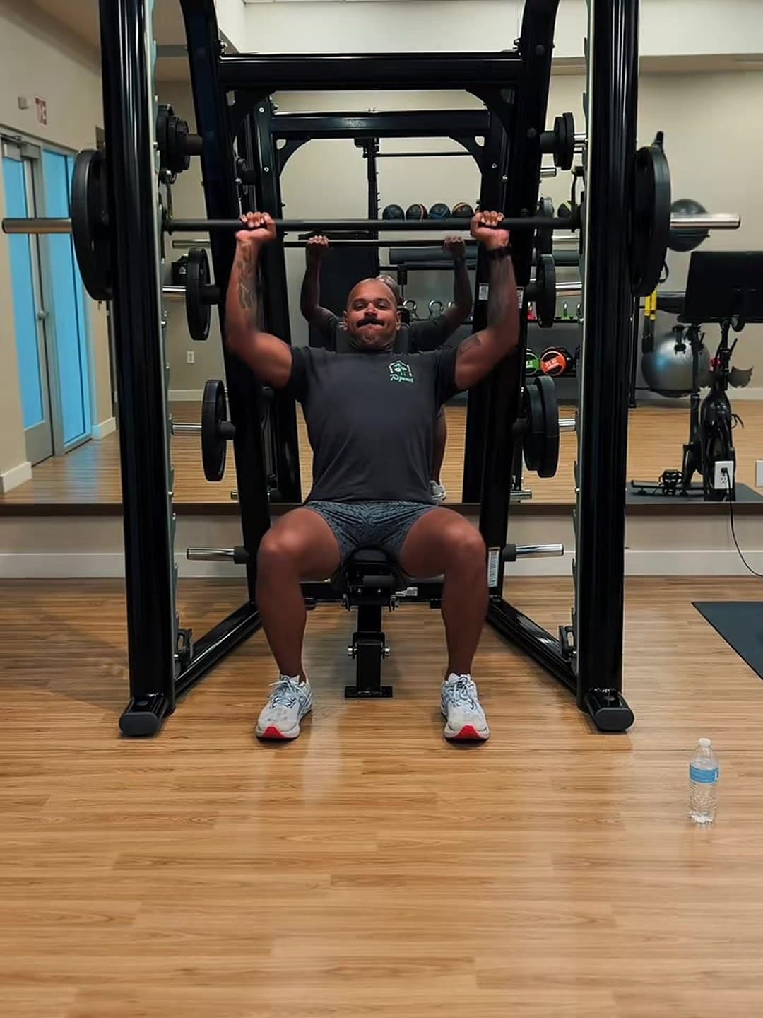 Kody doing a shoulder press in a hotel gym while traveling.